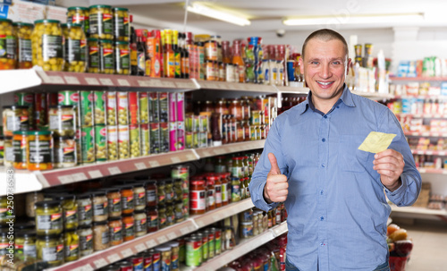 Man holding thumb up, making purchases with shopping list