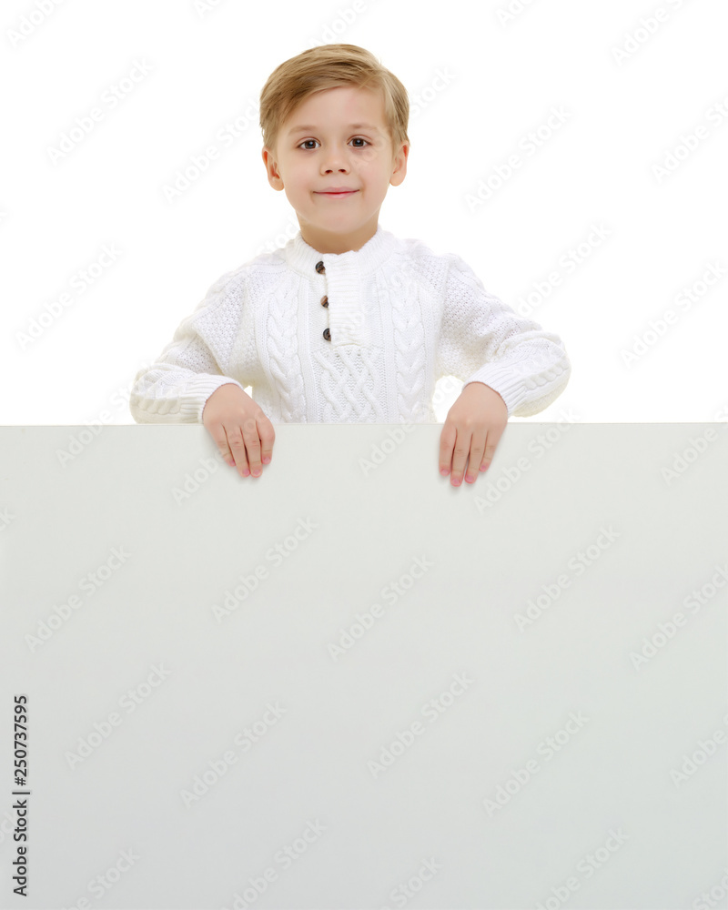 A little boy is looking from behind an empty banner. A little boy is looking from behind an empty banner.