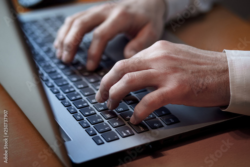 Male hands typing on a laptop keyboard © stivog