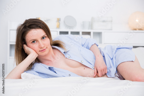 Girl in blue shirt playfully posing and relaxing in bed