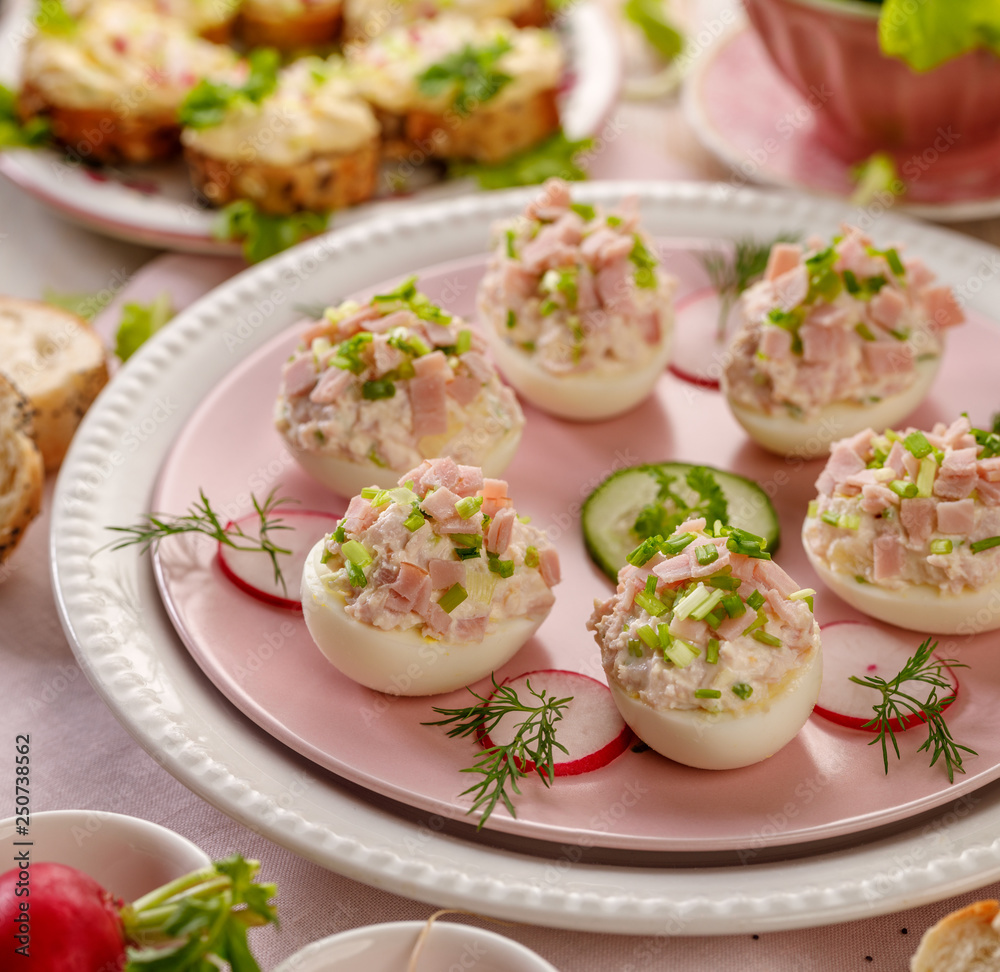 Deviled eggs, stuffed eggs filled with a paste made from smoked ham, mayonnaise, egg yolks and fresh chive on a plate.Tasty breakfast, appetizer for party or holiday meals Deviled eggs, stuffed eggs filled with a paste made from smoked ham, mayonnaise, egg yolks and fresh chive on a plate.Tasty breakfast, appetizer for party or holiday meals