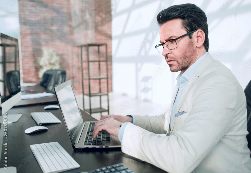 behind the glass.serious businessman typing on a laptop behind the glass.serious businessman typing on a laptop