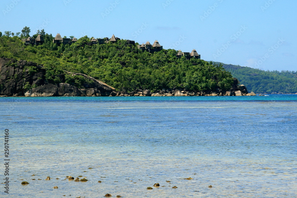 lagoon with clear blue water, tropical greenery and rocks with beach