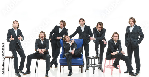 The eight identical handsome men in black suits differently pose on a white background  brutal man with long curly hairs  white shirts  business man  very stylish  blue leather chair  twins