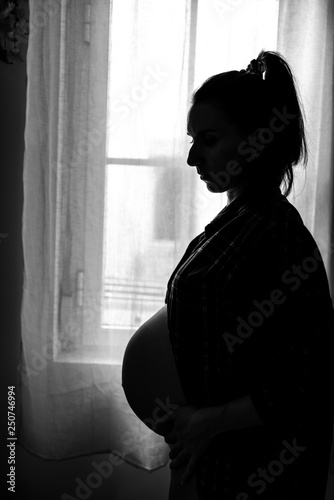Silhouette of Pregnant Woman Standing next to the Window.