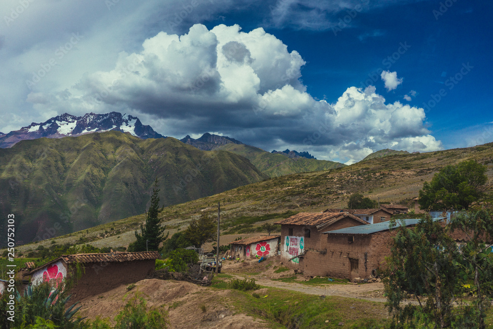 Buildings beneath beautiful clouds on the hillsides of Sacred Valley Peru
