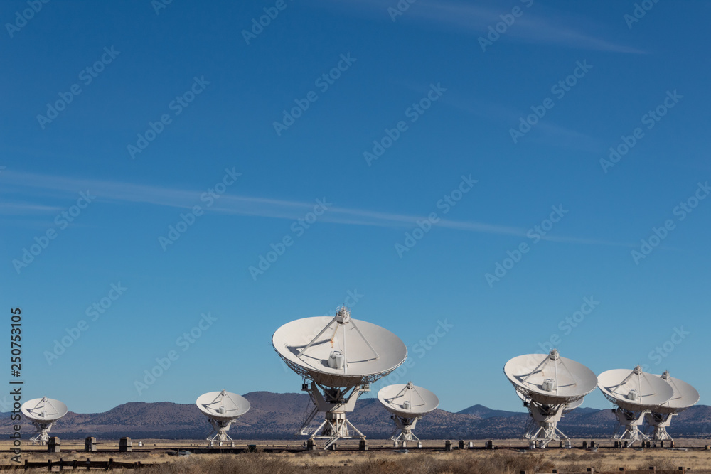 Very Large Array grouping of radio antenna dishes in New Mexico desert, blue sky copy space, horizontal aspect