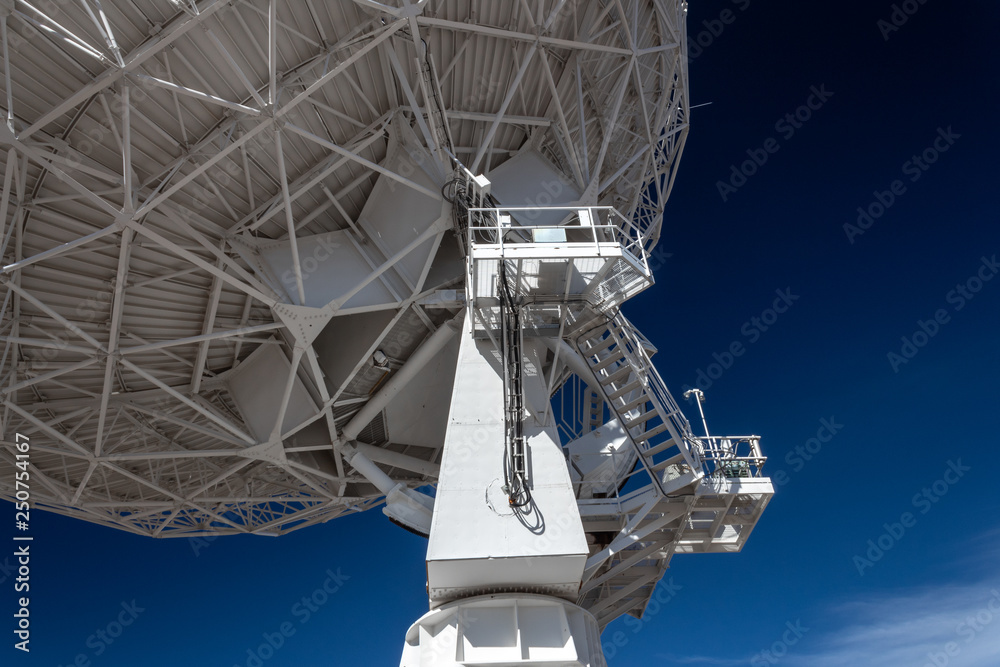 Very Large Array upright and trusses under radio astronomy observatory dish against blue sky, science technology engineering, horizontal aspect Very Large Array upright and trusses under radio astronomy observatory dish against blue sky, science technology engineering, horizontal aspect