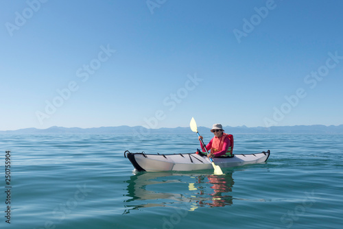 A female, baby boomer kayaking on the ocean near Kaiteriteri, New Zealand, on a calm, sunny day.