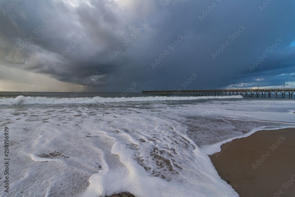 Sea foam and a stormy sky with ocean pier