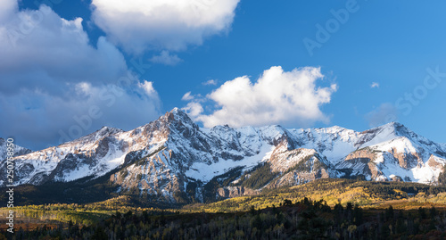 Mount Sneffels is within the Uncompahgre National Forest. An early fall snowstorm covers the mountain range with aspen groves in full colo