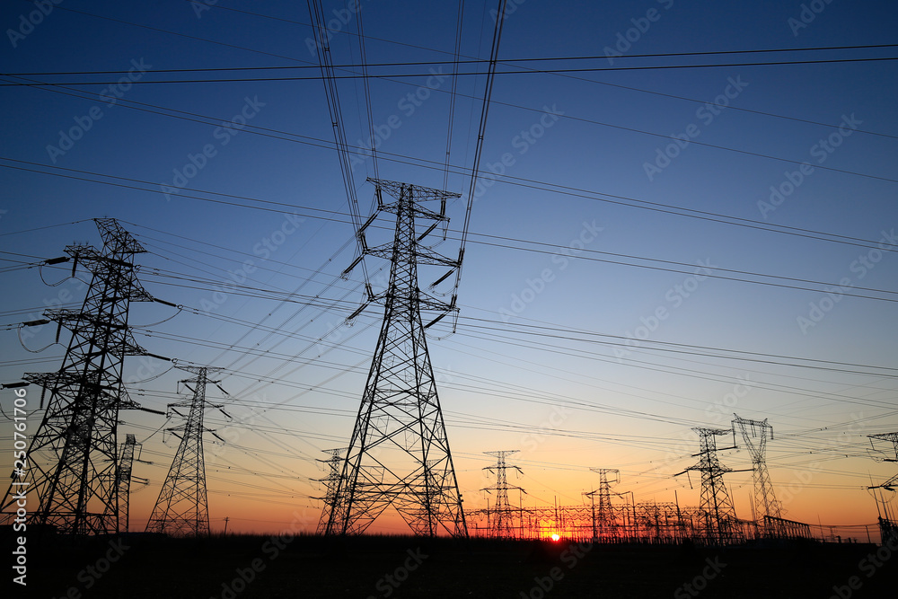 A high-voltage tower in the setting sun against the sky