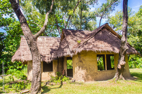 Earthen house under shade of trees. An earth house, also known as earth berm, earth sheltered home, or eco-house is an architectural style by use the natural terrain to help form the walls of a house.