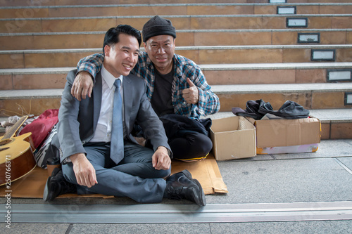 Businessman who lives as a friend with a homeless man without disgust and both smiles happily. Sharing concept