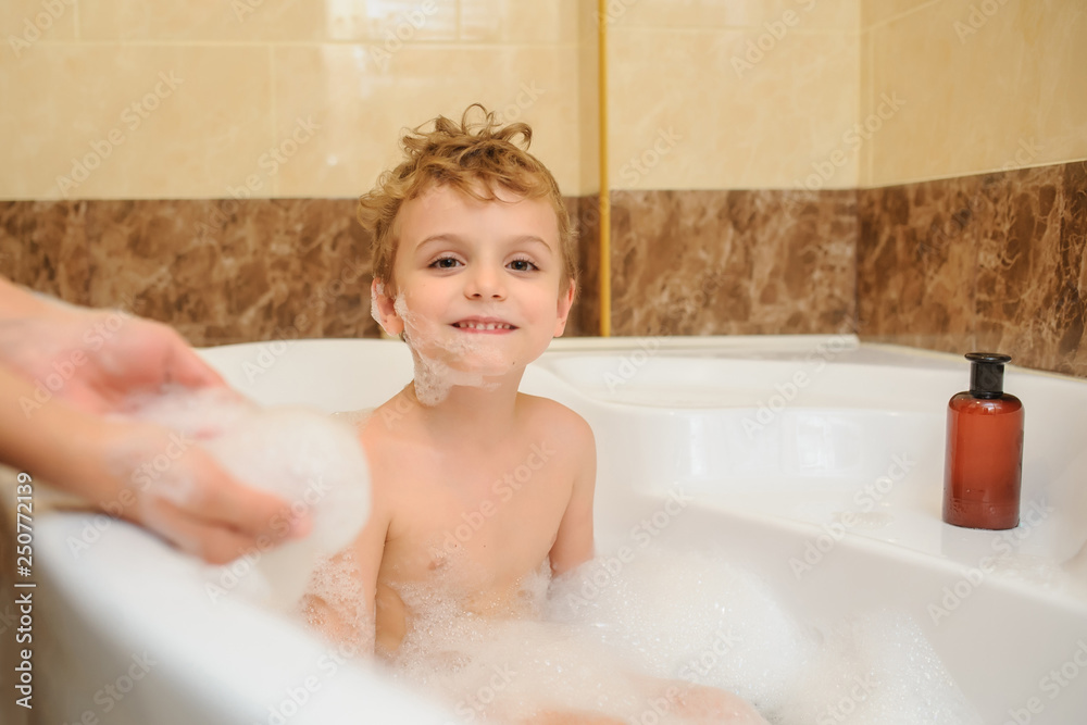 Little boy washing and playing in bathtub with foam and soap bubbles with his mother Little boy washing and playing in bathtub with foam and soap bubbles with his mother