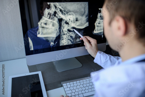 back view of a male radiologist examining neck x-rays (cervical vertebrae) on computer photo