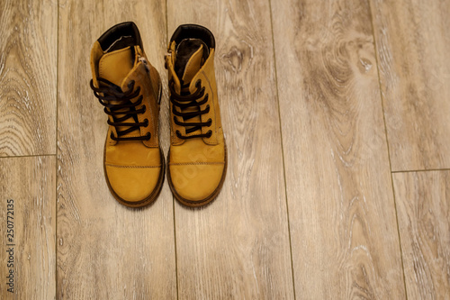 top view of a pair of yellow leather child shoes on a brown floor