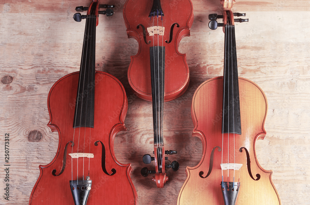 Fototapeta Three violins on wooden texture