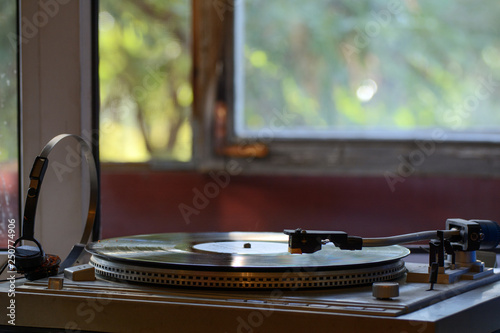 retro turntable with vinyl record standing in front of sunny window