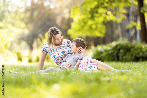 Mother and son sitting on a grass in park