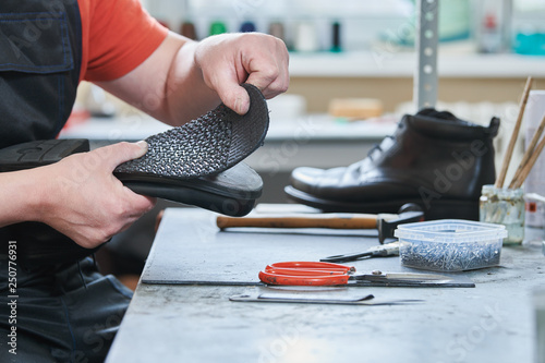 Shoemaker repair shoe. Glueing the sole for male footwear photo