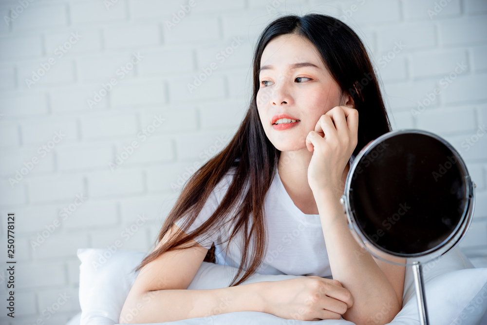 Asian teenage woman looking at mirror and squeeze acne problem on her face, skin care concept. Asian teenage woman looking at mirror and squeeze acne problem on her face, skin care concept.