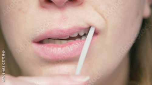 Woman swabbing cheek for DNA sample - 4k. Closeup on a cotton swab collecting samples of dna. Oral swab can be used for ancestry genealogy projects, genetic testing, donating bone marrow or databases.