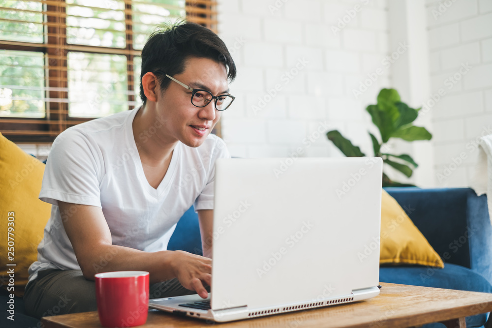 Fototapeta premium Young Asian man working with laptop at home