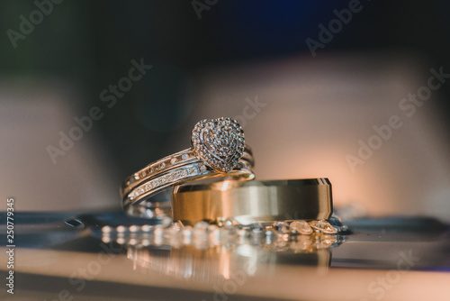 Gold heart wedding rings with diamonds on reflective table