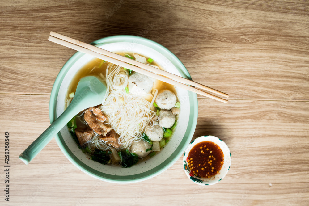 Noodle and soup with chilli sauce and pork meatball and boil pork with chopstick and spoon Noodle and soup with chilli sauce and pork meatball and boil pork with chopstick and spoon