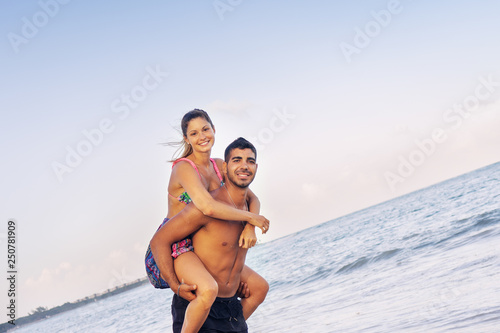 Lifestyle portrait of young couple piggyback ride at the beach © Guajillo studio