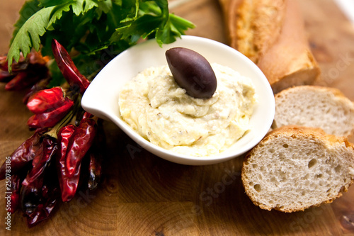 Traditional Tirokafteri in white plate decorated with chili, white bread and parsley. photo