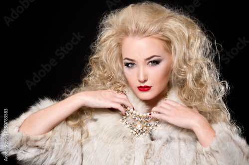 Fototapeta Naklejka Na Ścianę i Meble -  Beautiful blonde woman with curly hairstyle and bright makeup, perfect skin, cosmetology. Sexy vogue woman in fur and jewelry.