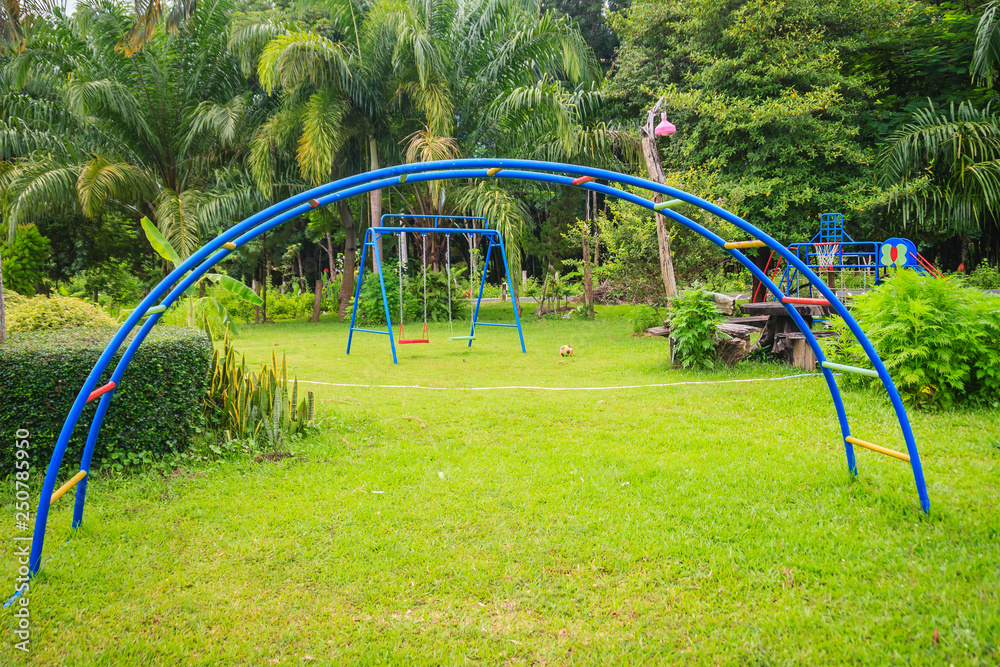 Playground equipment in the backyard for kids with soccer goal net and football on green grass field background. Playground equipment in the backyard for kids with soccer goal net and football on green grass field background.