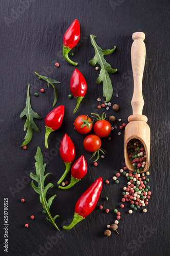 Different spices with tomato and  peppers on a black background