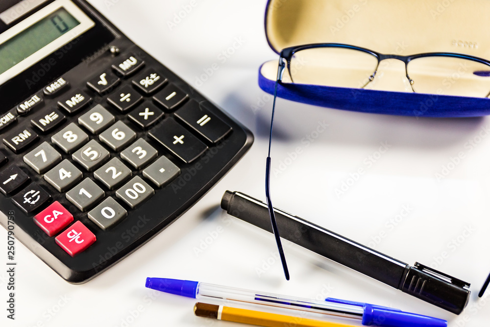 Calculator, glasses, pens and pencil on white table. Workplace office worker. Calculator, glasses, pens and pencil on white table. Workplace office worker.