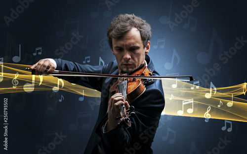 Young male musician playing on his violin with musical notes around photo