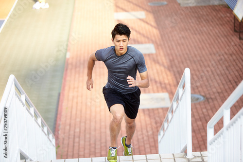 young asian athlete training running using outdoor steps photo