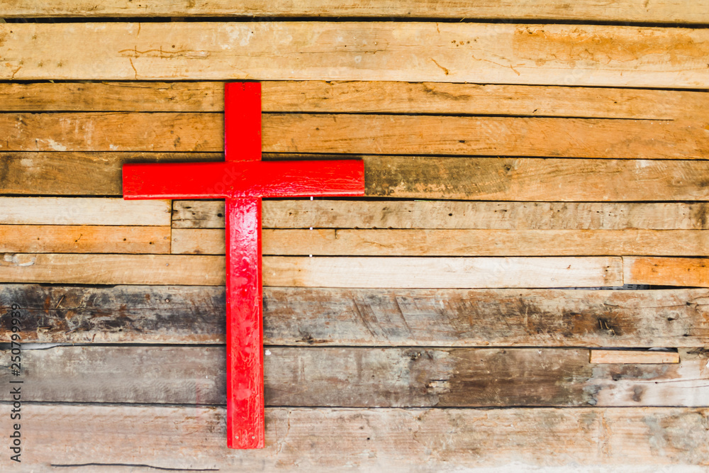Red wooden cross on wooden sheet background