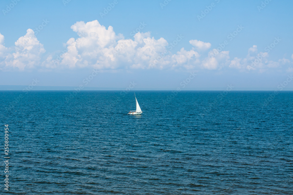White sailboat on the water surface on a Sunny day .