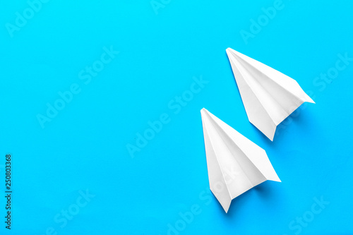 Flat lay of white paper plane and blank paper on pastel blue color background