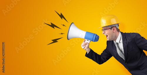 Young architect constructor yelling with megaphone and copyspace