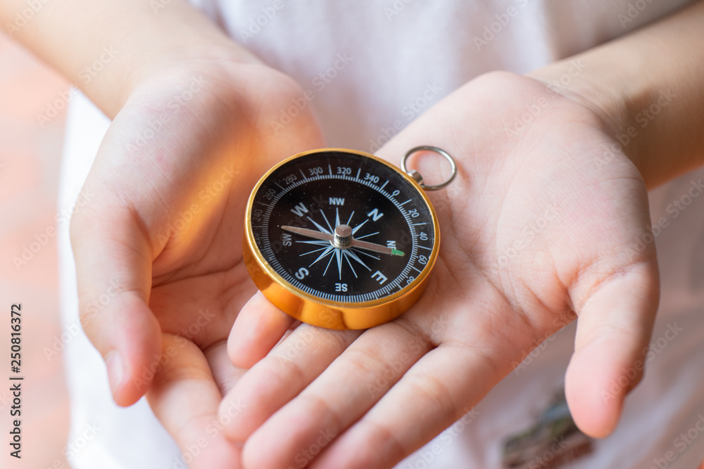 Compass in kid hand, giving direction concept Compass in kid hand, giving direction concept