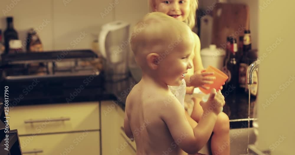 Little siblings play in the kitchen sink. Little siblings play in the kitchen sink.