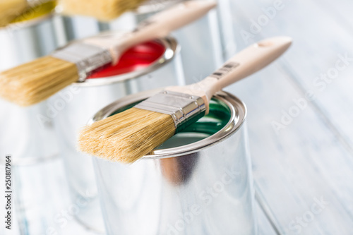 Fototapeta Naklejka Na Ścianę i Meble -  Close-up brushes lying on multicolored paint cans.