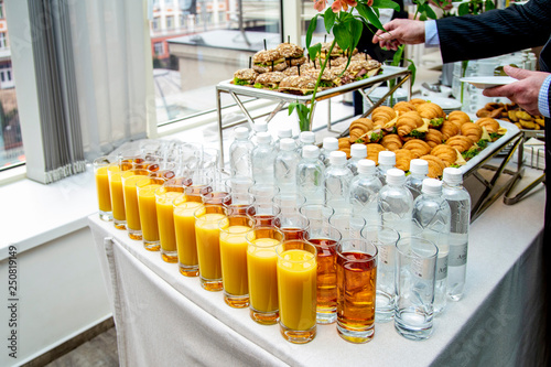 juices in glasses, mineral water on the table against the background of dishes  at catering event on some festive event, party or wedding reception