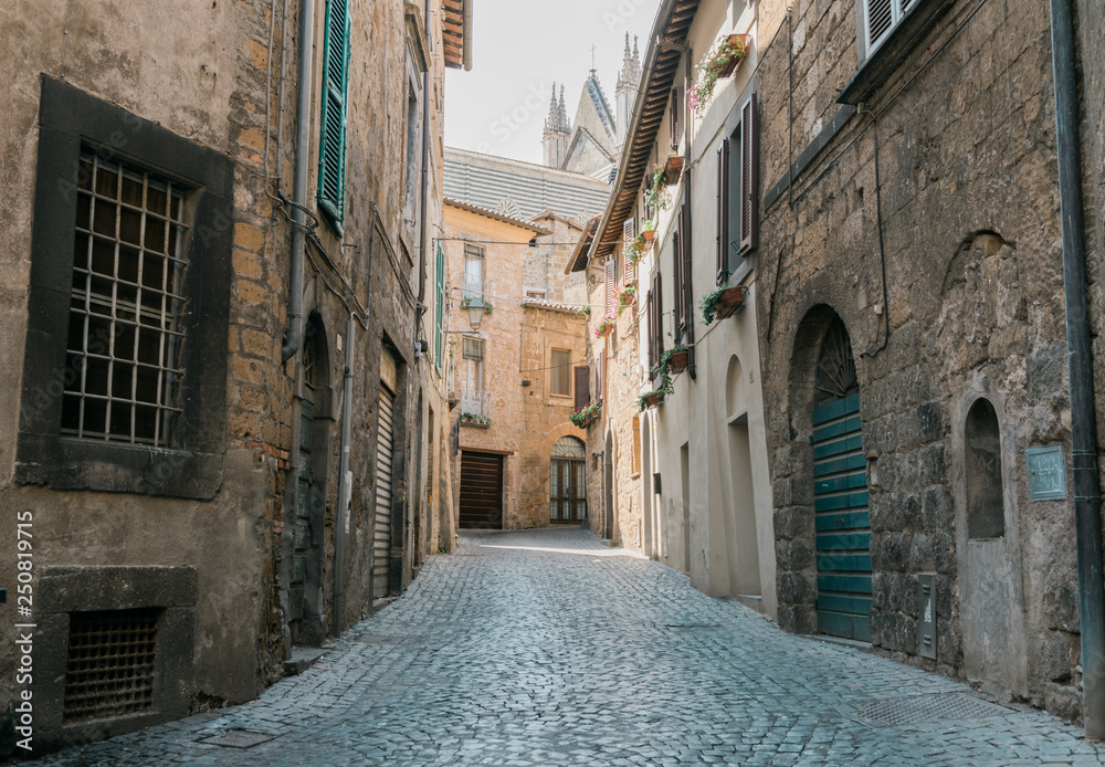 Medieval cozy narrow cobbled street with stone buildings in Italy. 