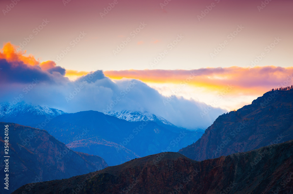 Mountain peaks with clouds at sunset. Altai, Siberia, Russia
