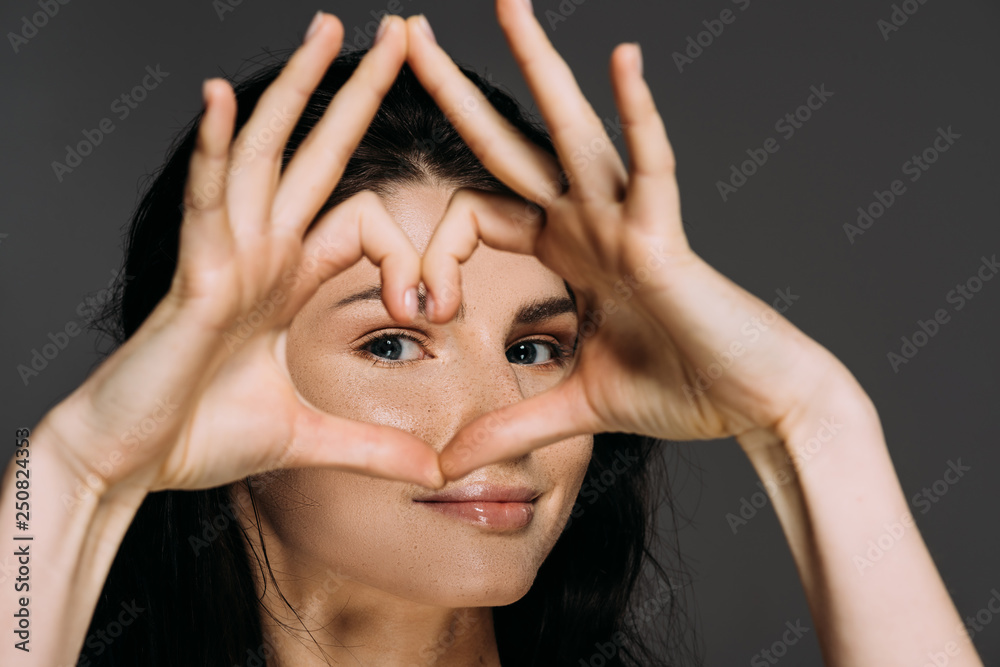 Fototapeta premium beautiful tender woman showing heart sign isolated on grey