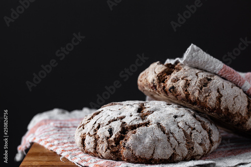 Two loaves of traditional finnish rye bread with raisins and seeds on linen towel. Artisanal bread. Healthy food concept.